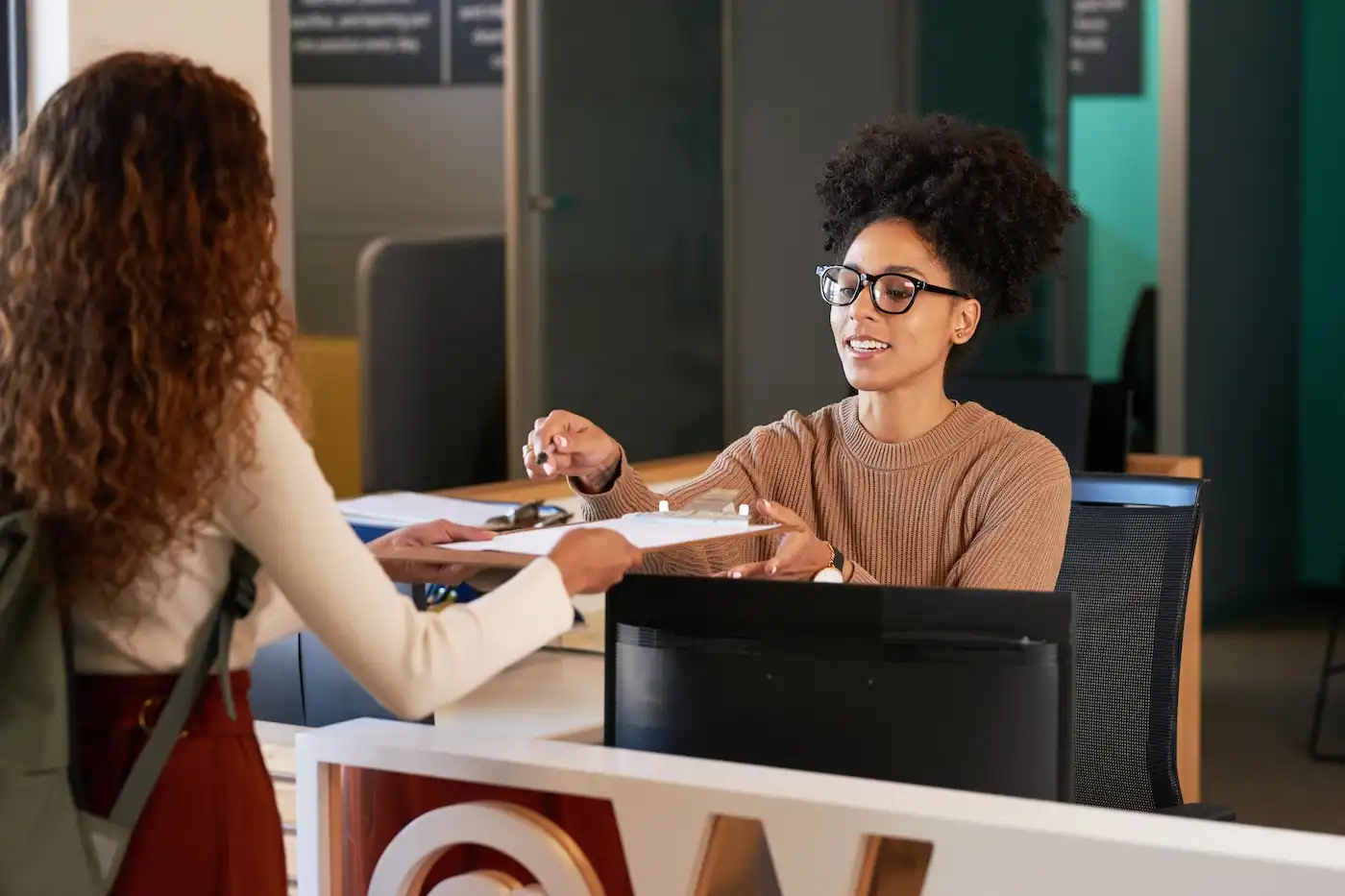 one woman giving another woman a clipboard to fill out