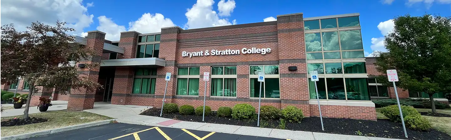 Exterior of Bryant & Stratton College building with brick facade, large windows, and clear blue sky above.