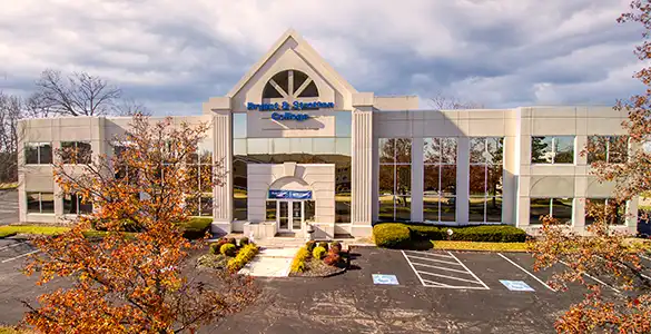 Two-story office building with "Smith & Solomon Training" sign, multiple windows, and autumn trees in the foreground.