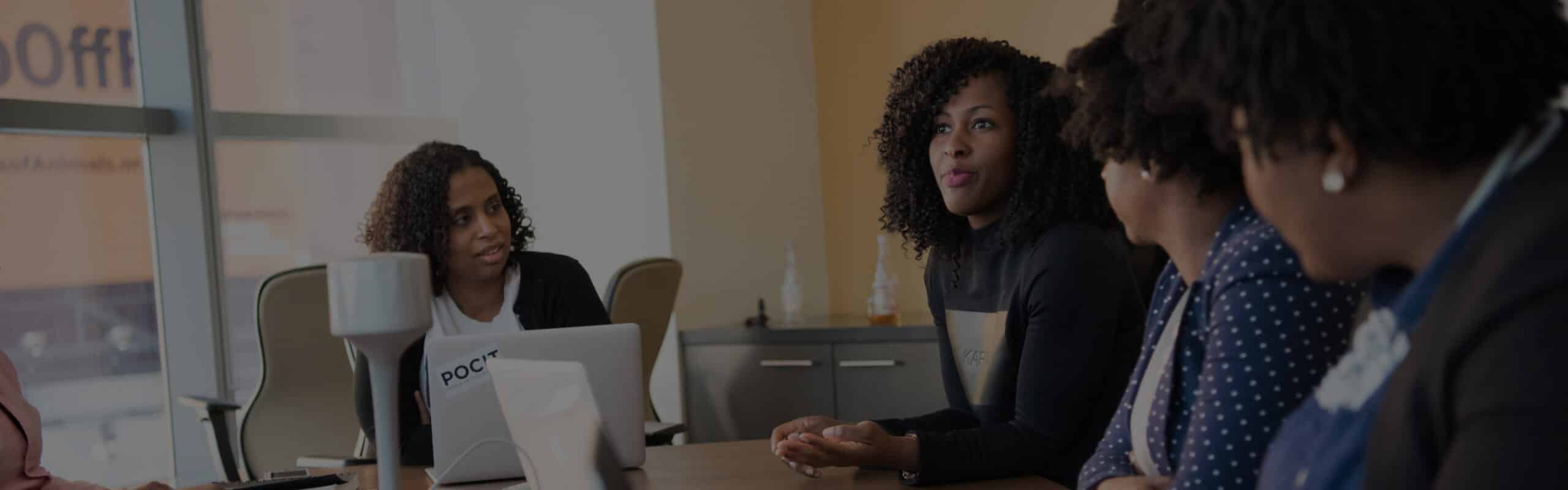 A group of people having a discussion in a conference room, with one person speaking and others listening attentively.