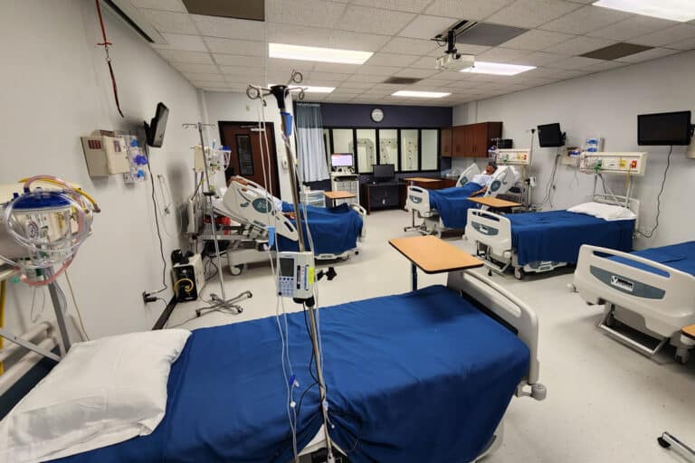 A medical simulation lab with hospital beds, monitors, and medical equipment used for training healthcare students.