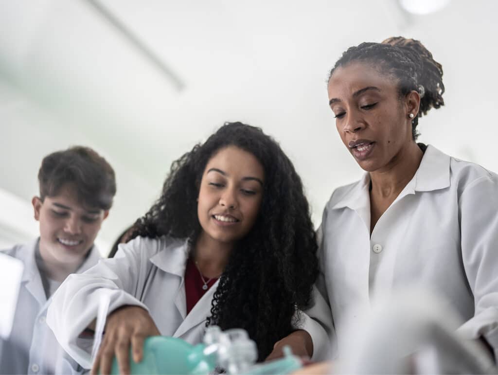 Three scientists in lab coats working together on an experiment with medical equipment in a laboratory.