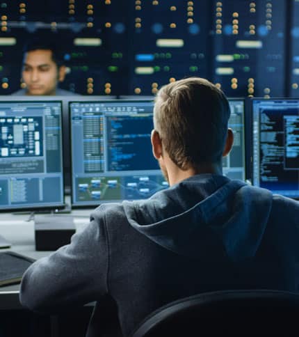 A cybersecurity specialist analyzing data on multiple screens.