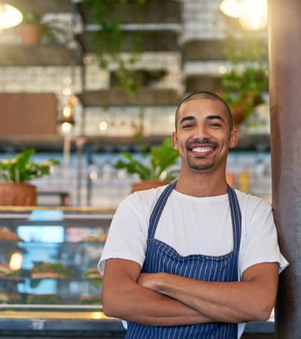 A smiling entrepreneur standing confidently in a modern cafe.