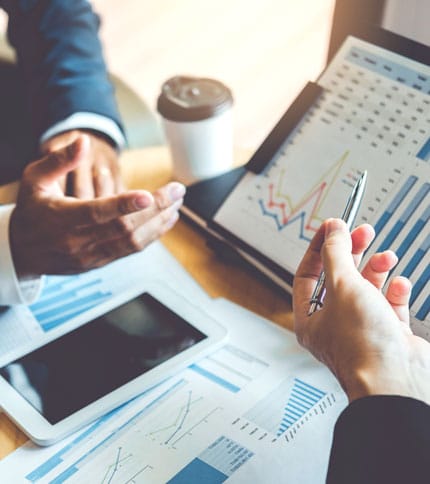 Two professionals discussing financial charts and graphs during a meeting.