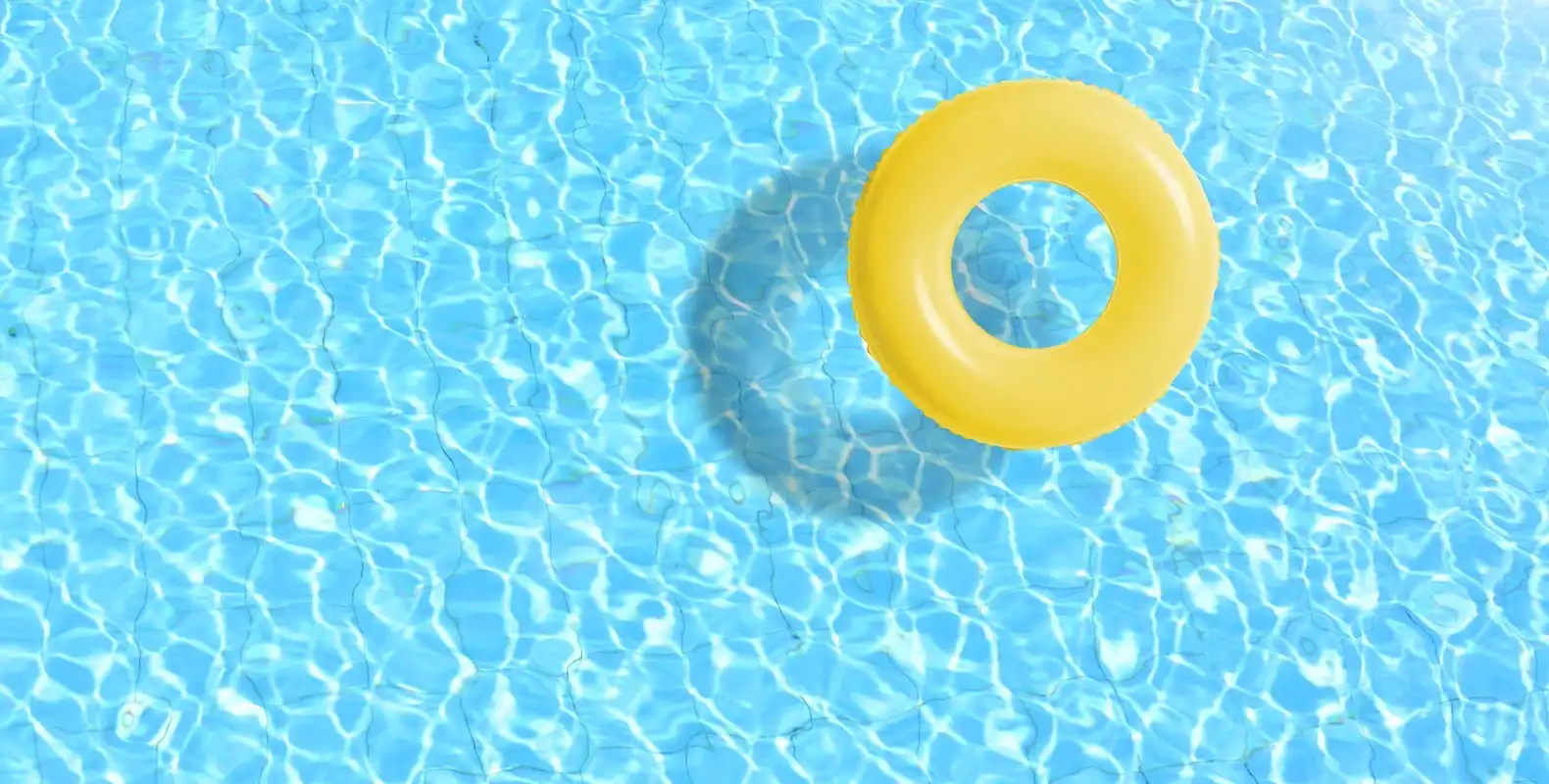 Bright yellow inflatable ring floating on clear blue pool water.