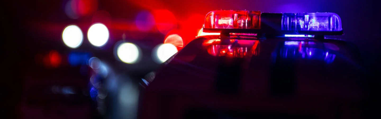 Close-up of emergency vehicle lights flashing red and blue in a dark setting.
