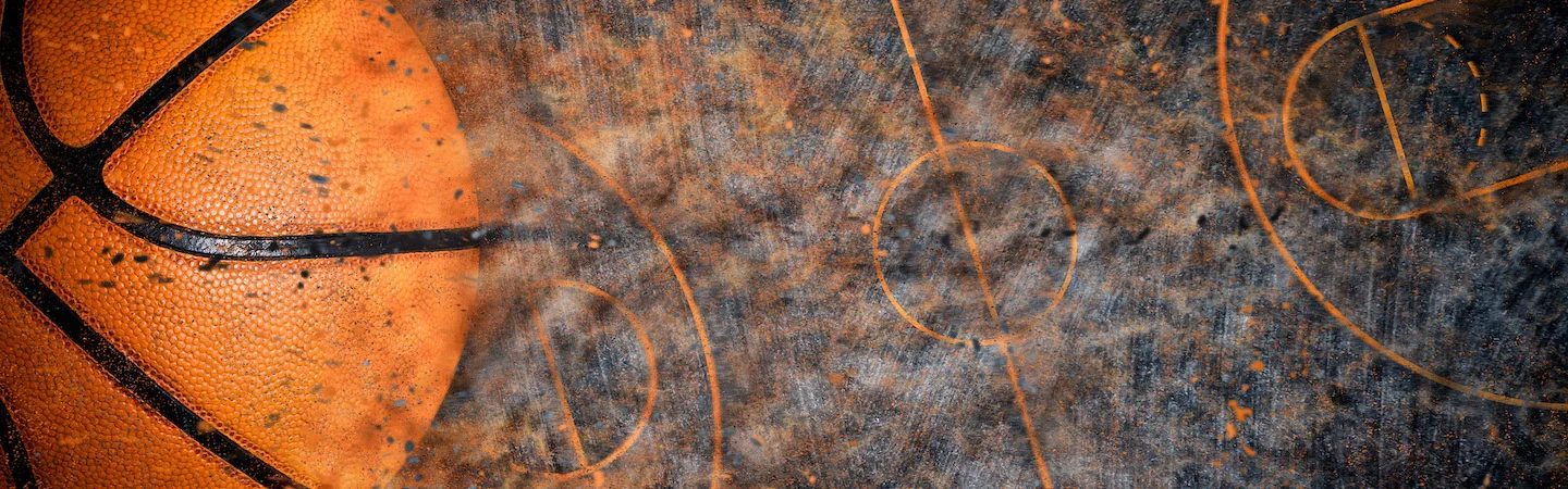 Close-up of a basketball on a worn court featuring multiple faded court markings.