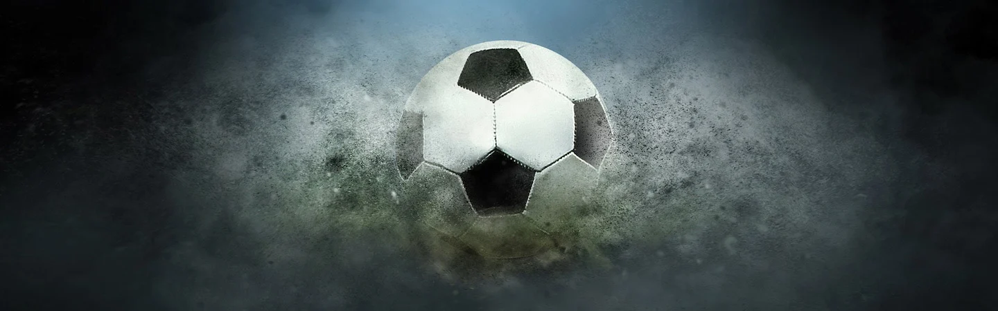 A soccer ball in mid-air surrounded by a cloud of dust or smoke against a dark, misty background.