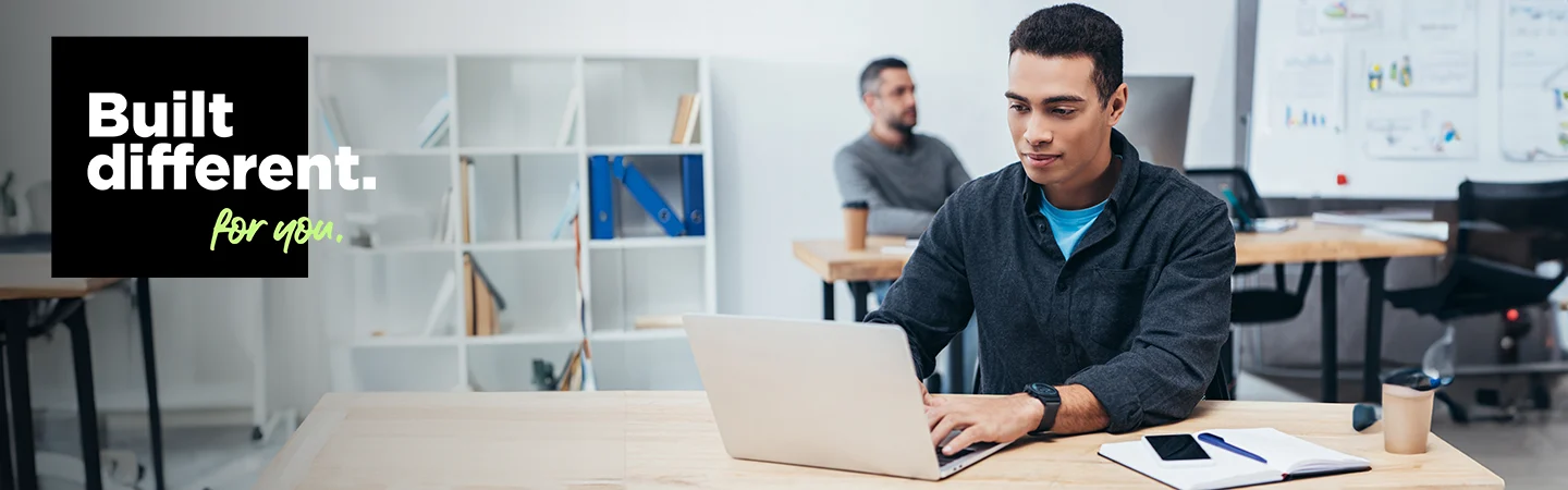 Man working on a laptop in a modern office, with text "Built different. for you." on the left side of the image.