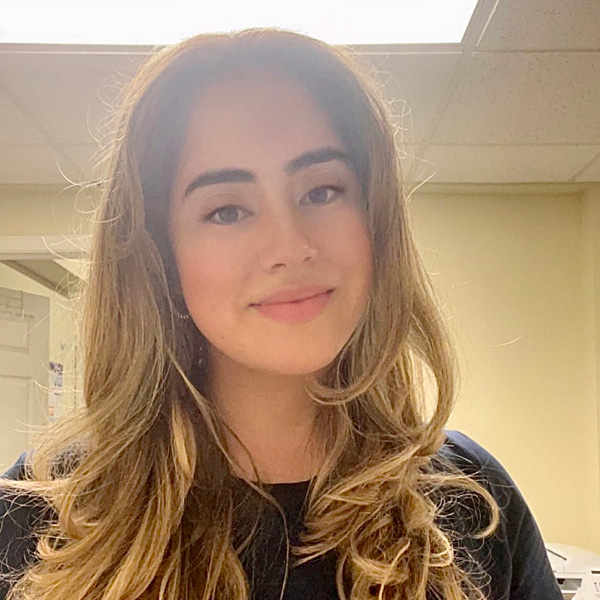 Smiling person with long, wavy hair in a well-lit indoor setting.