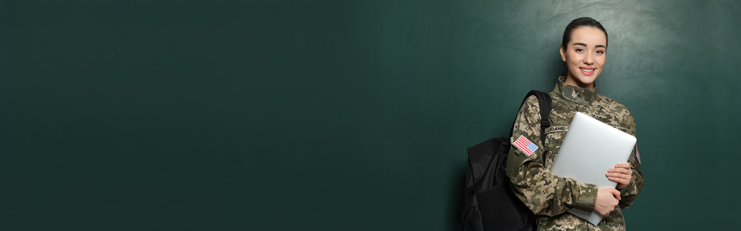 Woman in military uniform holding a laptop and a backpack, smiling in front of a dark green background.