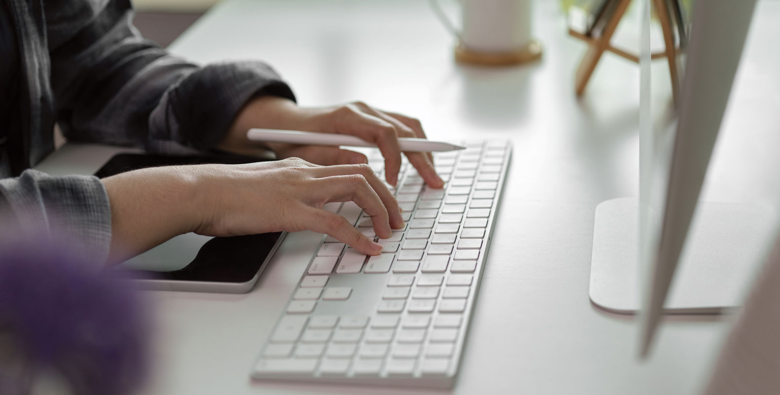 A person typing on a computer keyboard while holding a stylus, representing the precision and skills required for medical billing and coding.