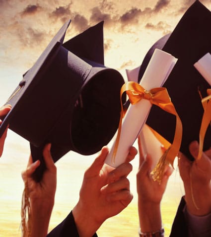 Several hands raise graduation caps and diplomas tied with yellow ribbons against a dramatic sky, celebrating achievement and success earned through online associate degrees.