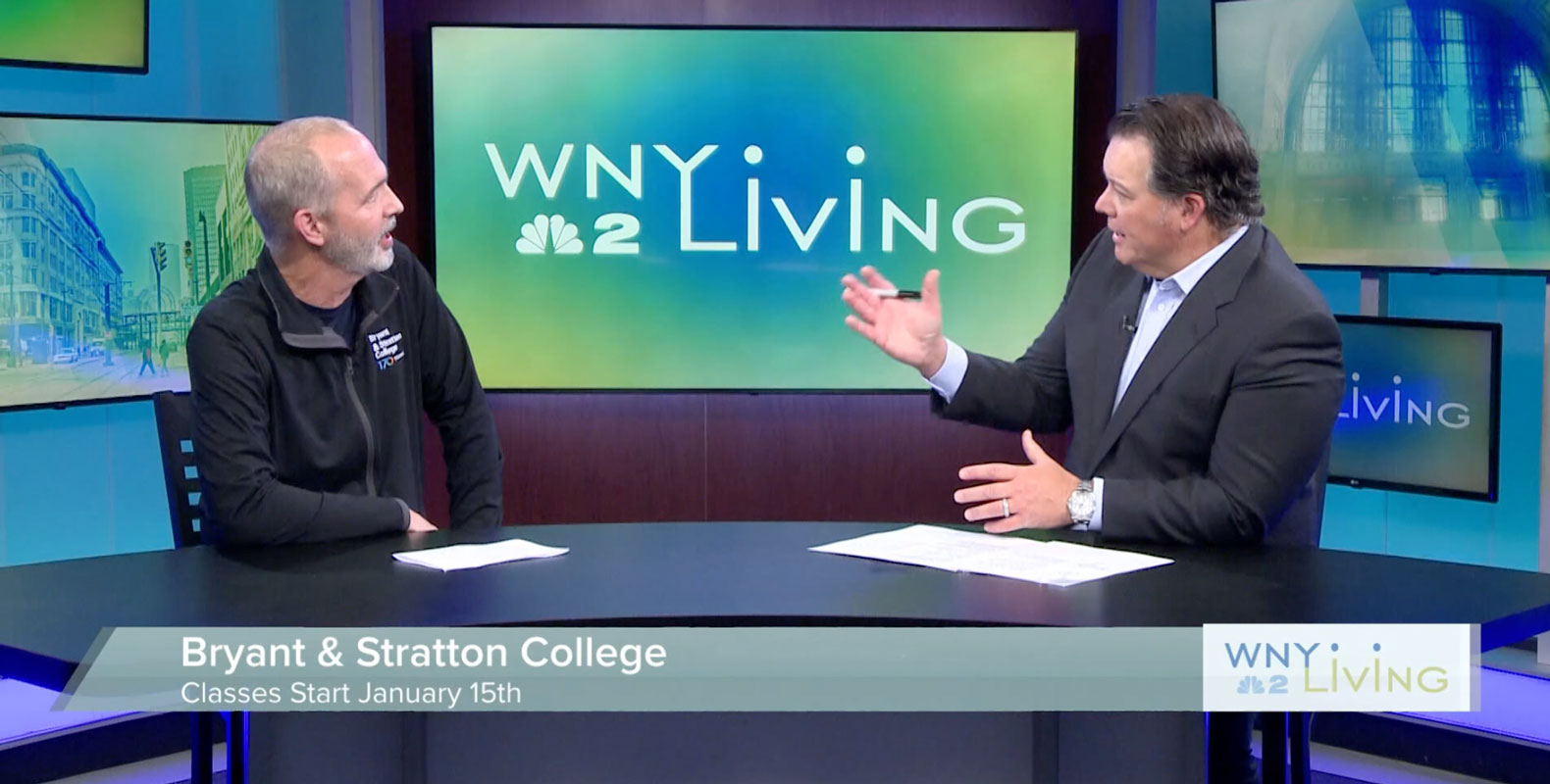 Jeff Tredo sits at a news studio desk during a WNY Living segment discussing Bryant & Stratton College classes starting January 15th.